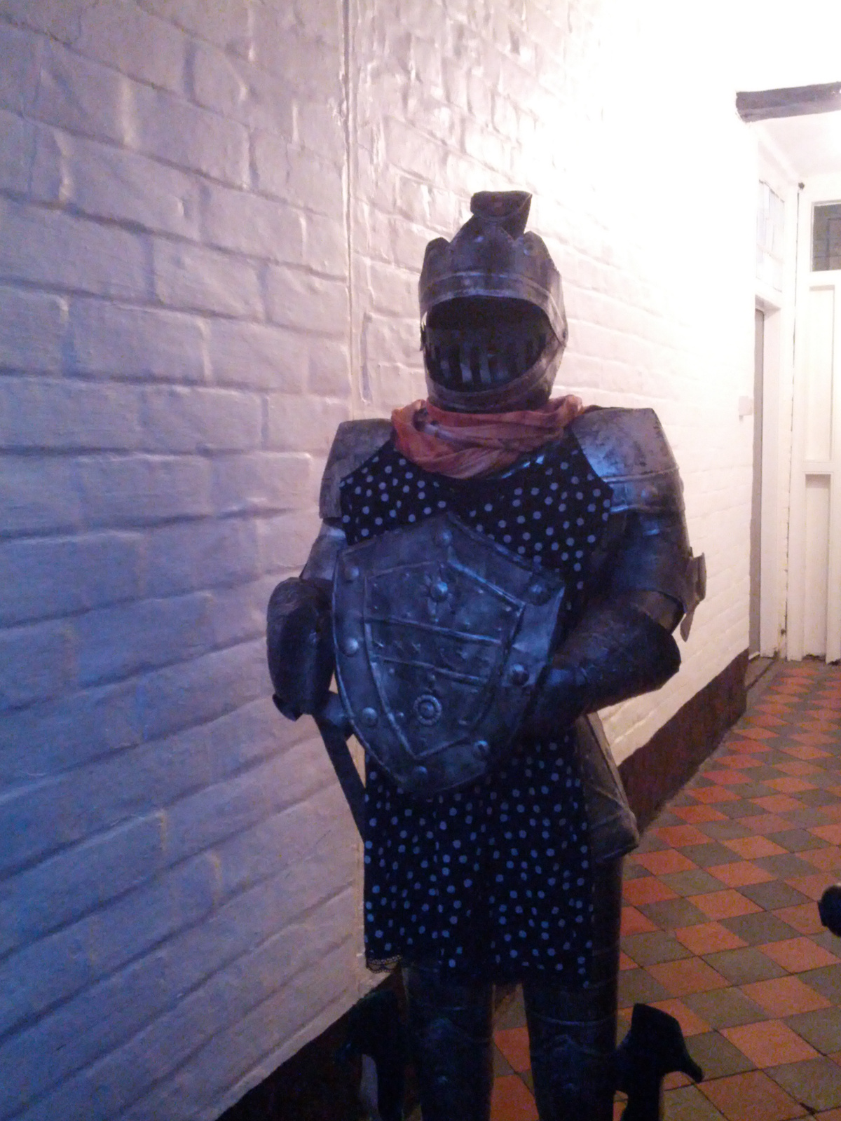 A suit of armour, wearing a dress, standing in a passageway