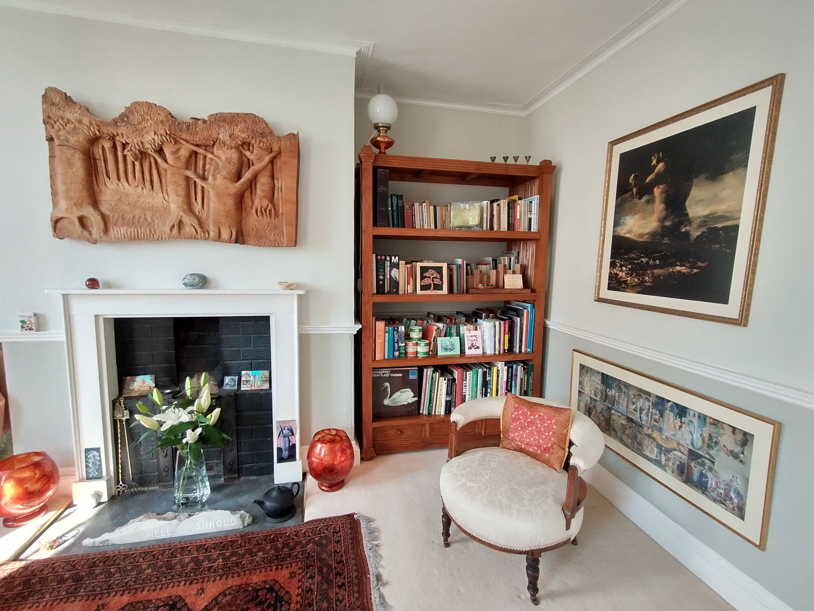 View of living room with fireplace, bookcase and artwork